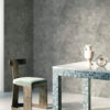 Carta da parati NUCLEO effetto intonaco grigio in ambiente contemporaneo con tavolo rivestito in mosaico.