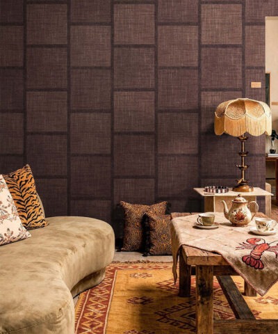 Carta da parati geometrica TRAMA in tonalità scura con disegno a quadrati, divano beige e arredamento in stile rétro.